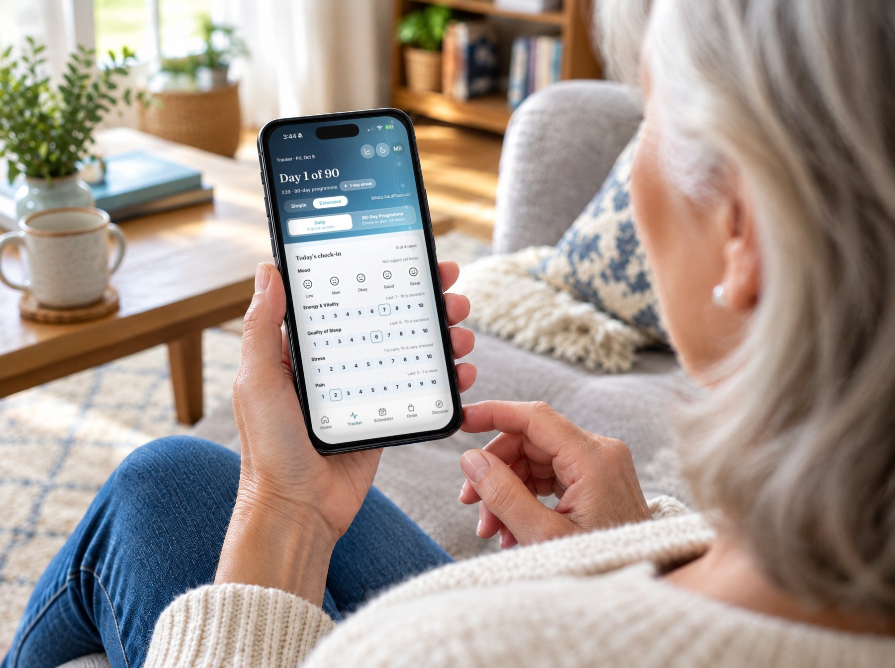 Over the shoulder of a woman on her sofa, holding a phone showing the DFS Health tracker